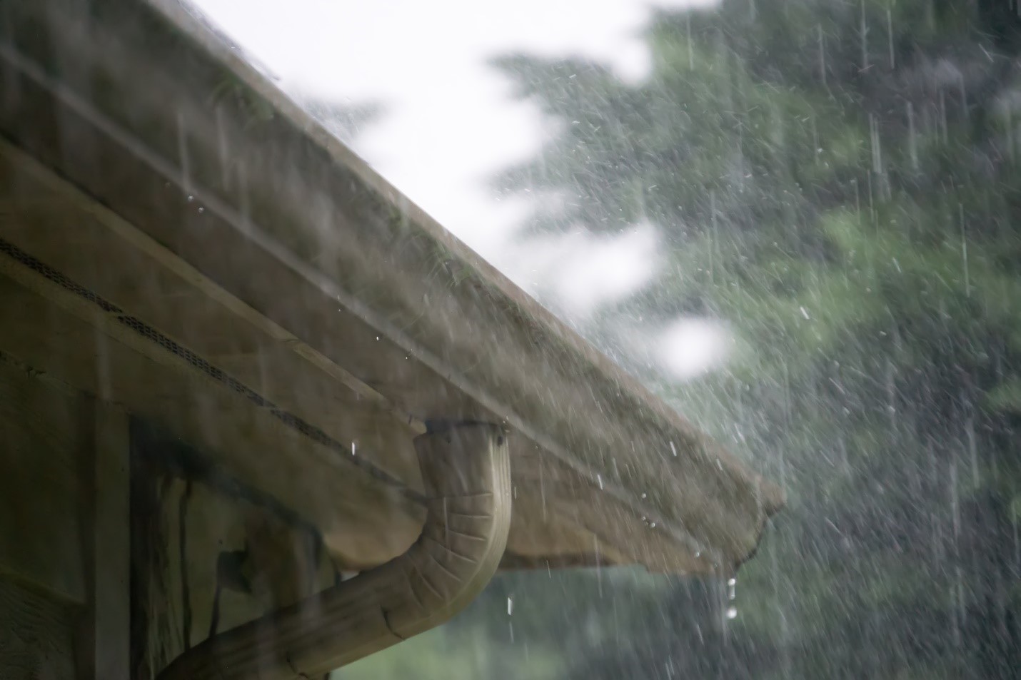 Hard rain falling on the corner of a home's gutters and drain spout.