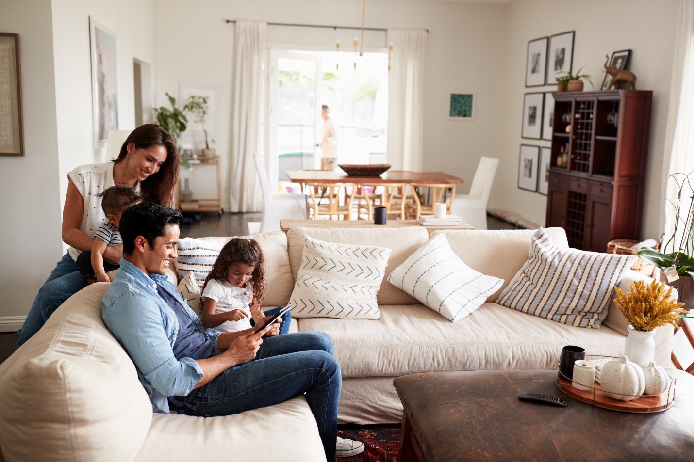 A young Hispanic family smiling at an iPad together on the couch in their sitting room.