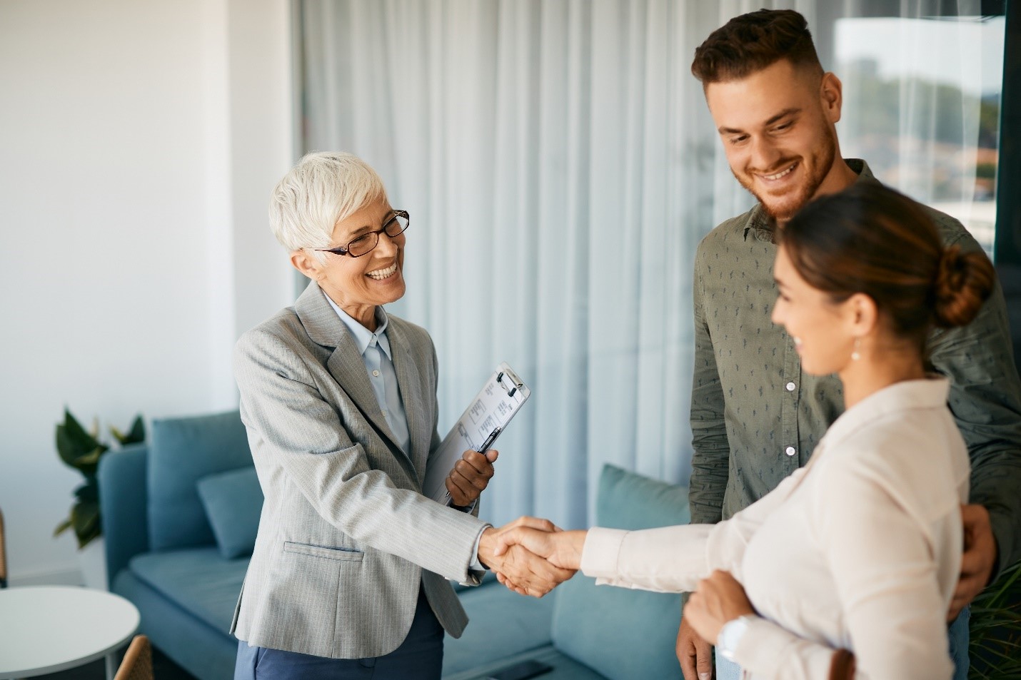 A real estate agent smiling as they shake hands with a client.