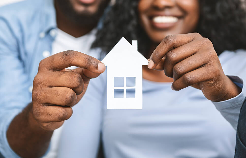 close up of african coupleholding wooden house