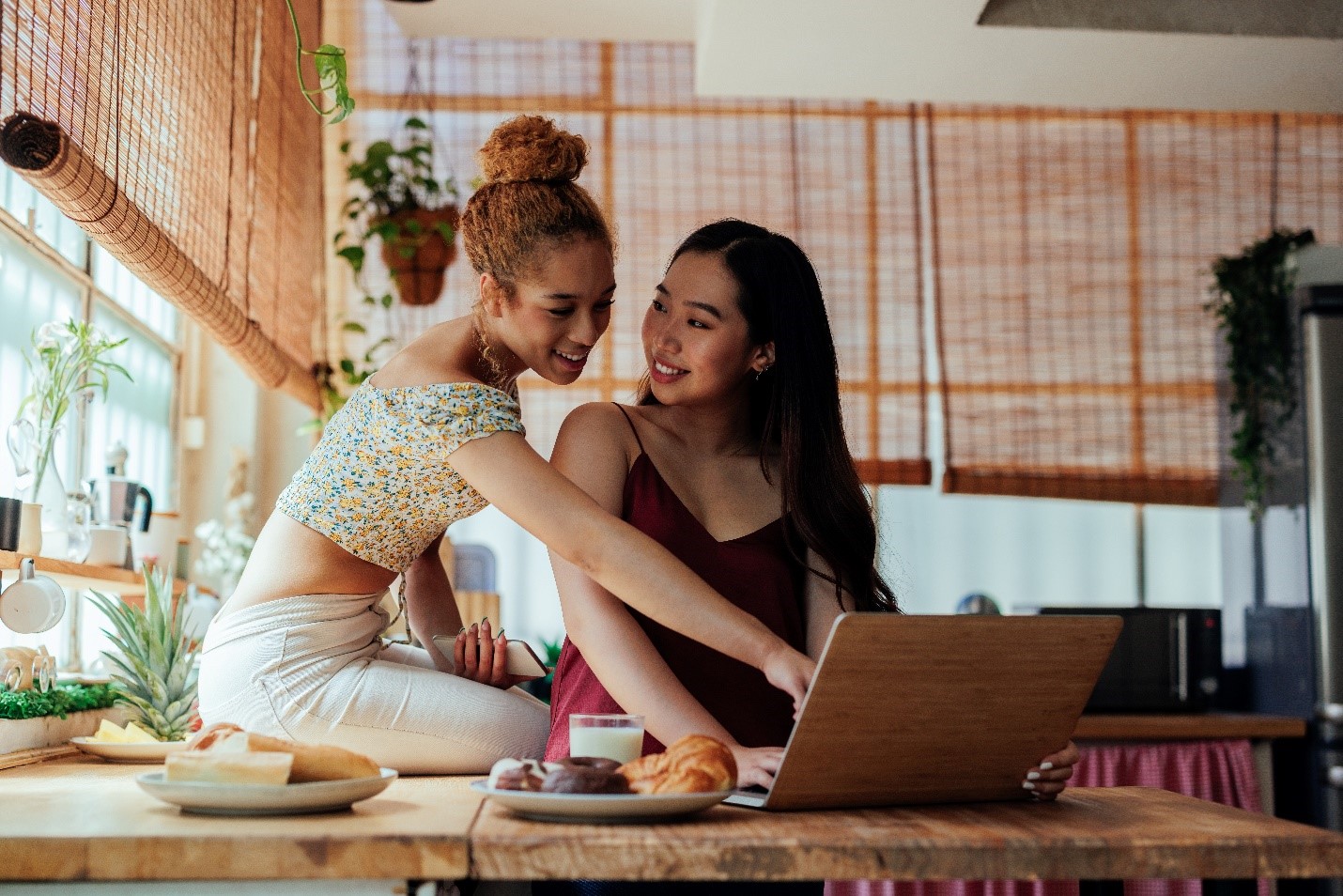 Two girlfriends looking at a laptop together.