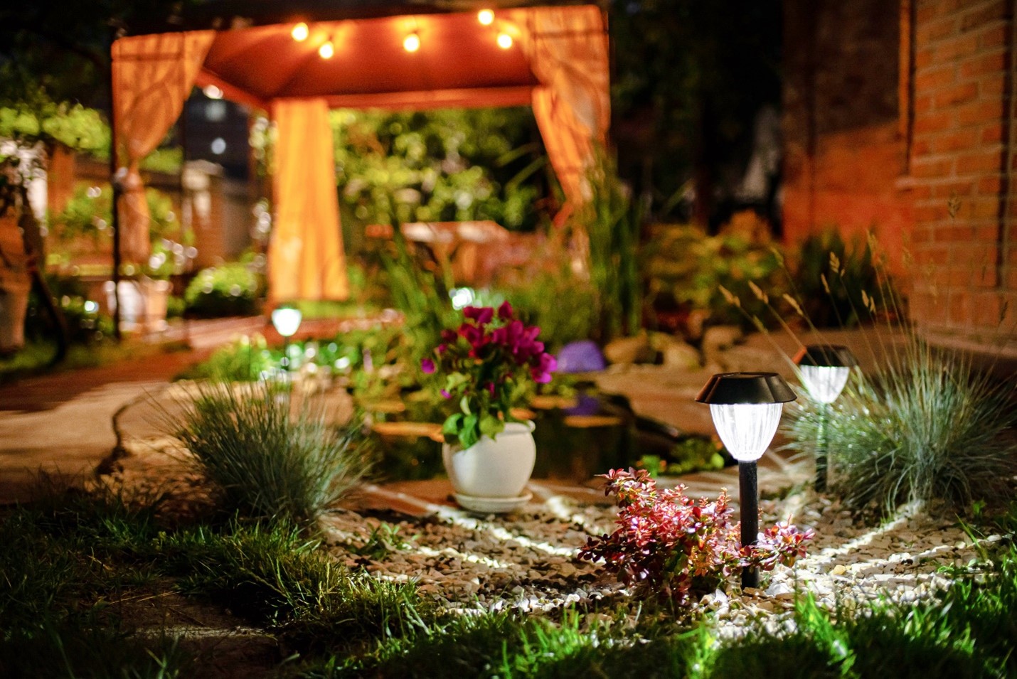 Outdoor path lights casting a white glow among landscaping.
