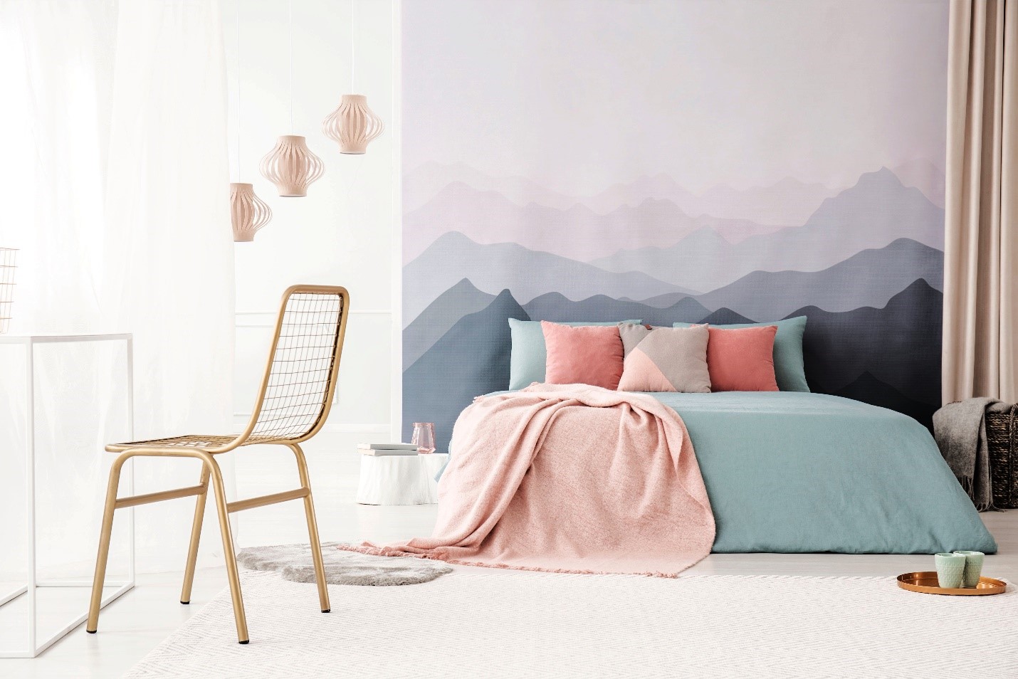 A bedroom with a mural of ombre mountains and bright paper lighting.
