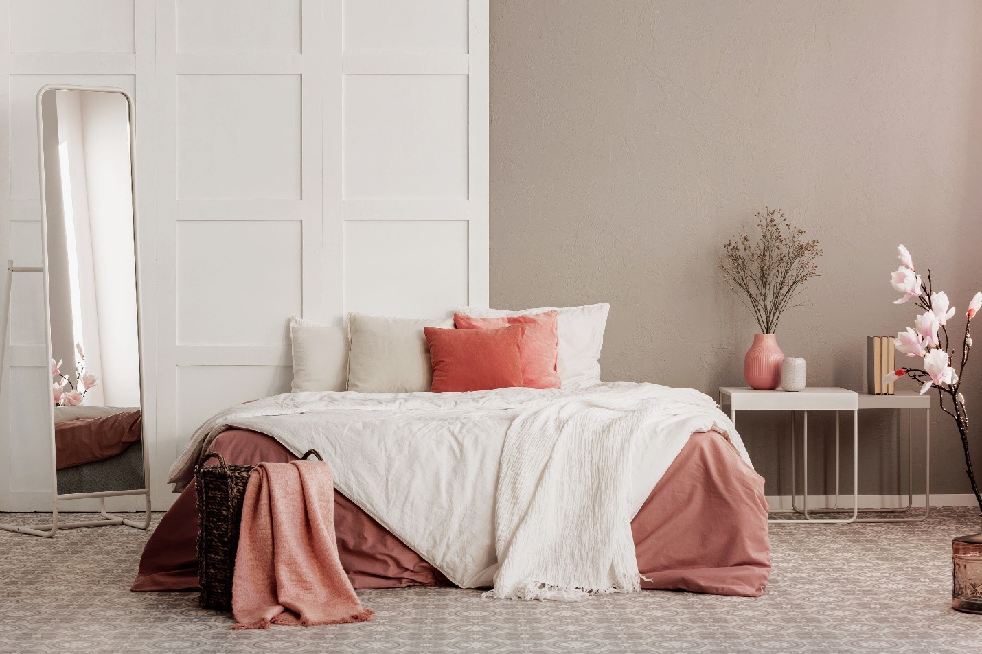 A neutral painted room with pink and linen bedspread.
