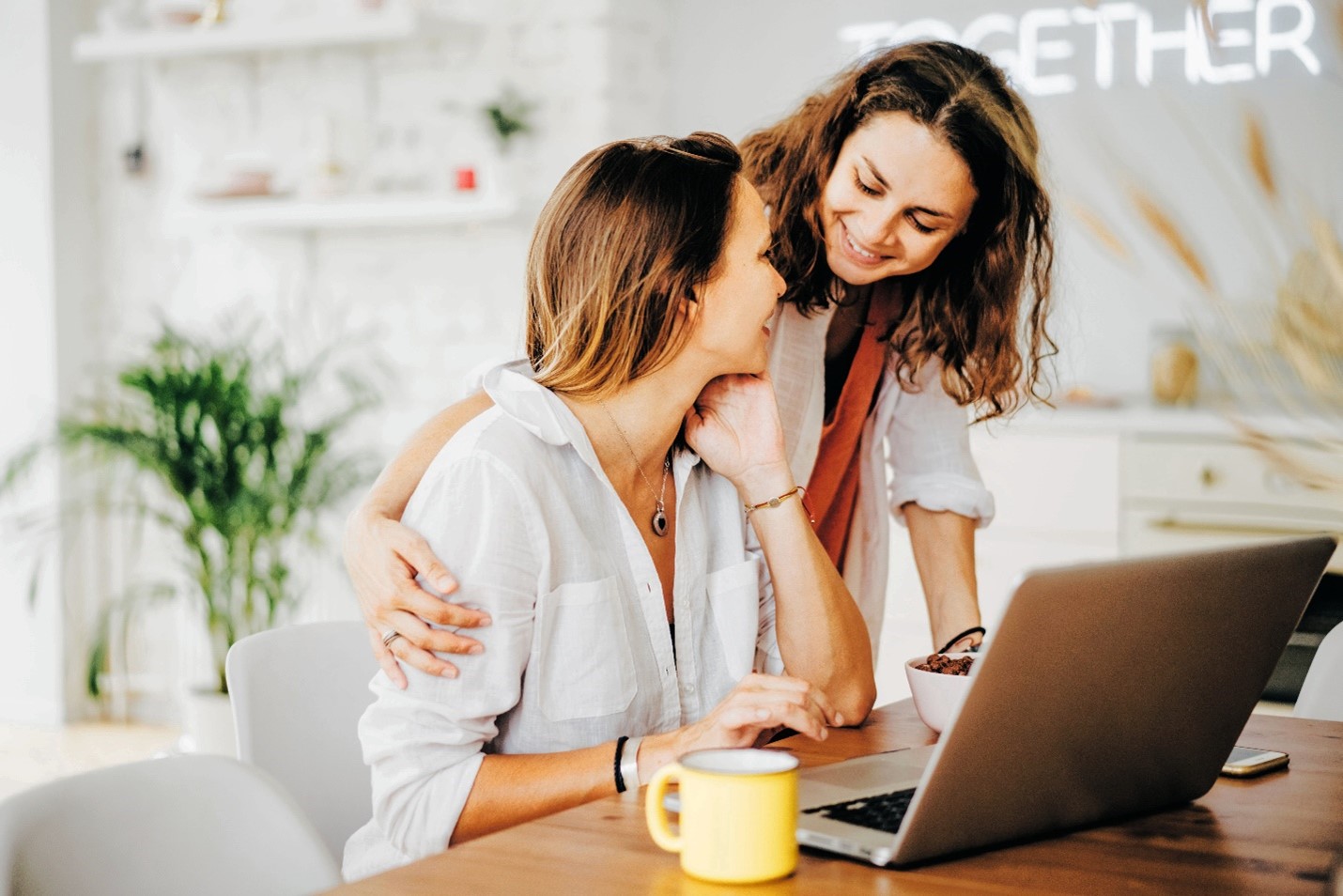 Two women look at a laptop together.