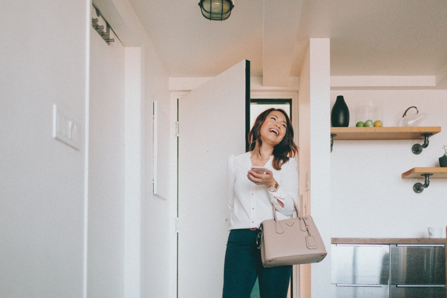 A smiling Asian woman entering her home.