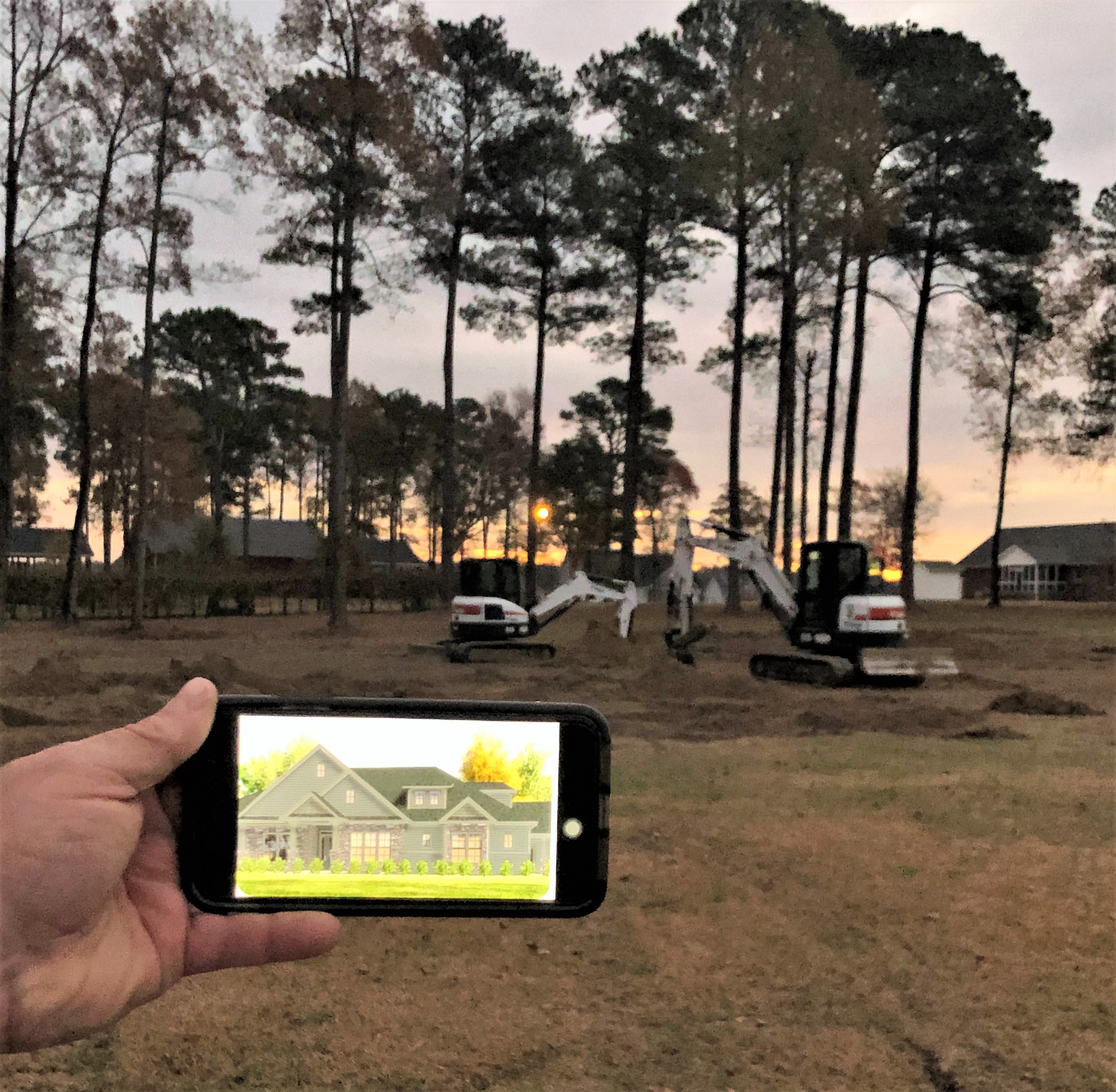 A photograph of the lot for the future Cummings North Carolina home with an iPhone depicting what the completed home would look like.
