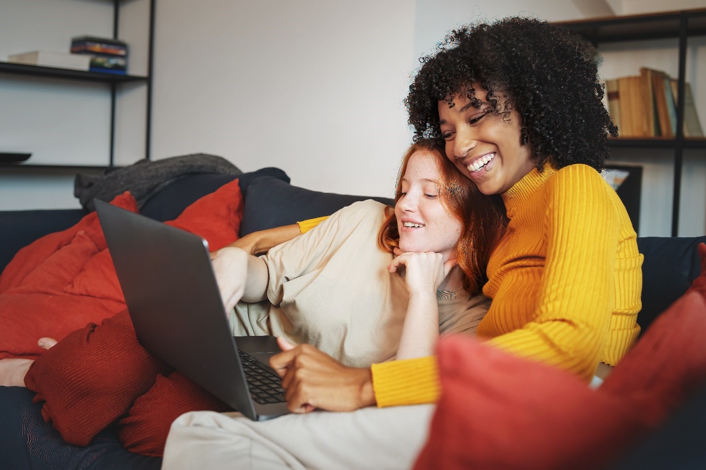 Two people cuddling and smiling at a laptop.