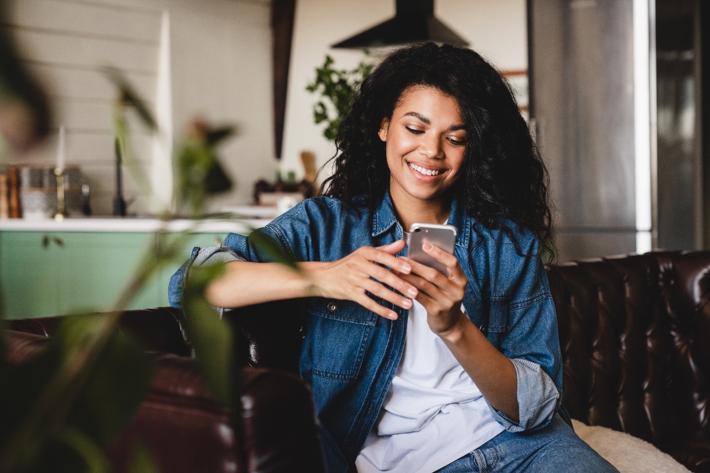 A young person smiling down at her phone.