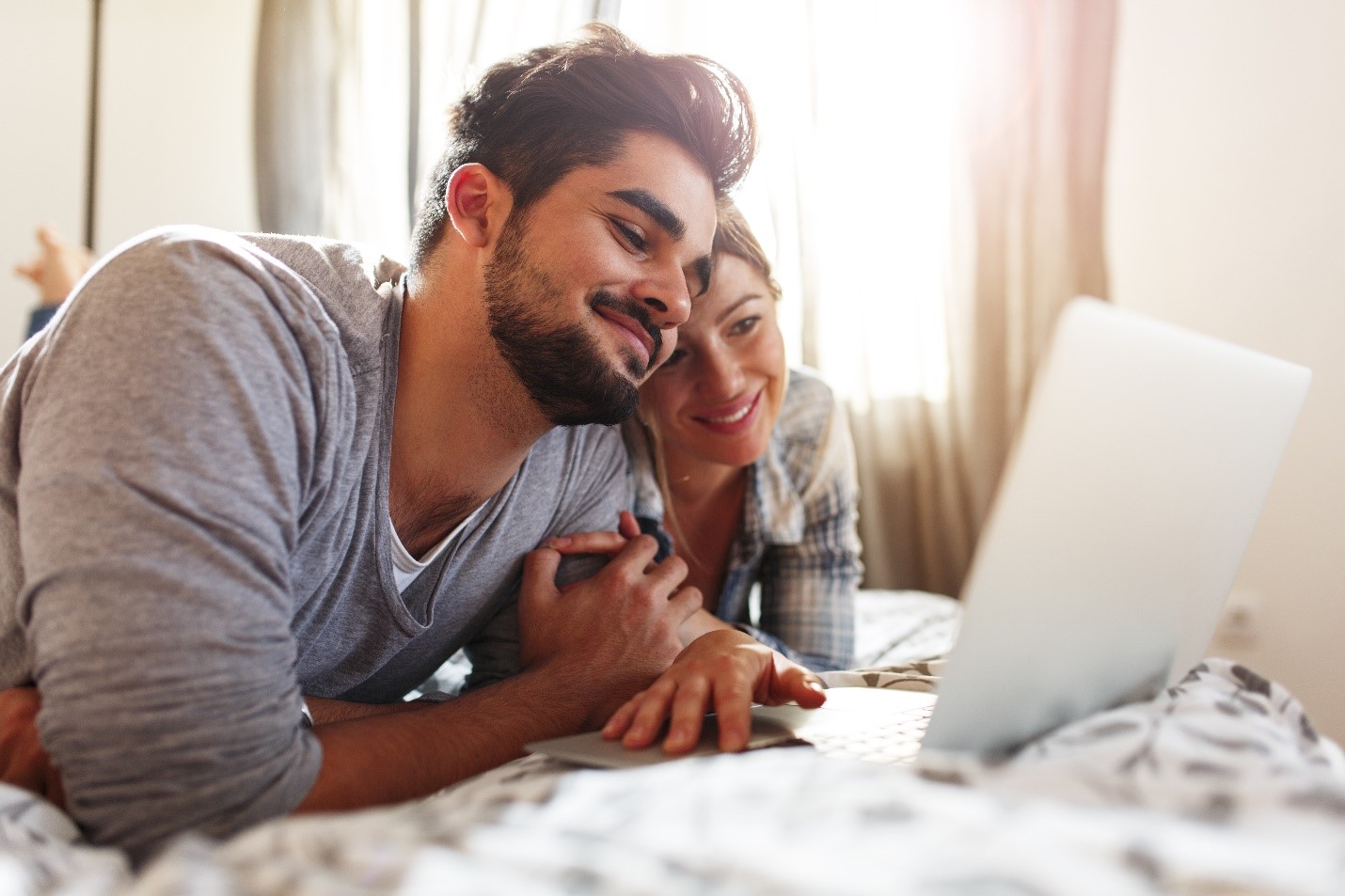 A couple holding hands as they pay their mortgage online.