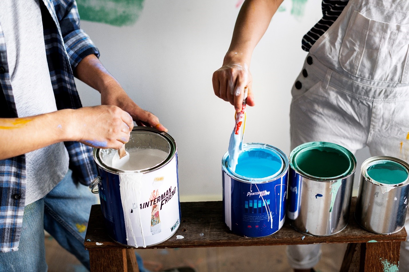 Faceless photo of two people dipping brushes into paint cans.