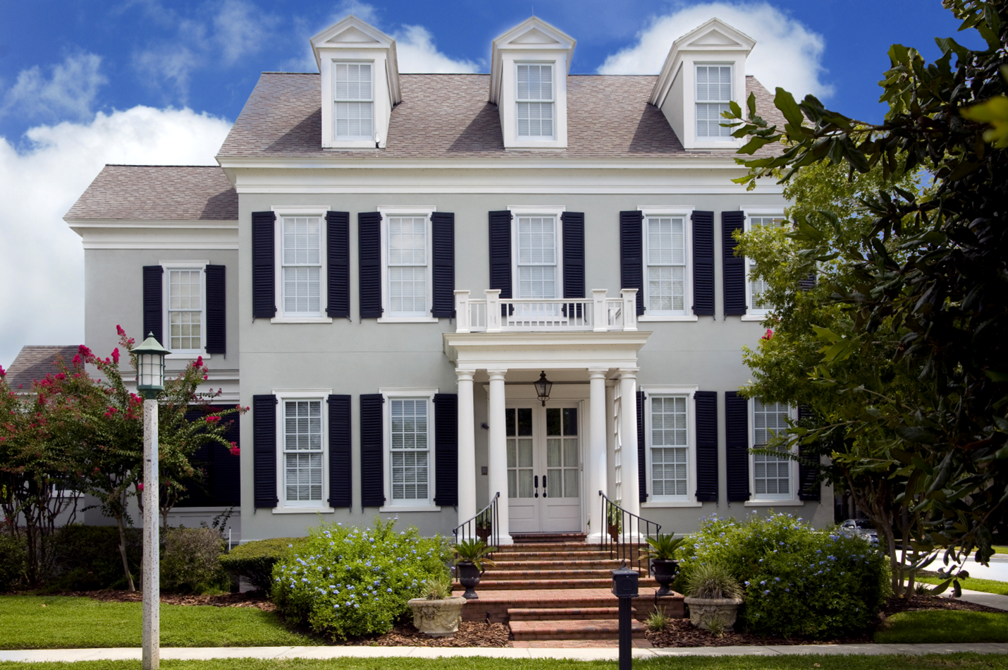 A colonial home with flat walls, strong columns, and three dormers above the top floor.