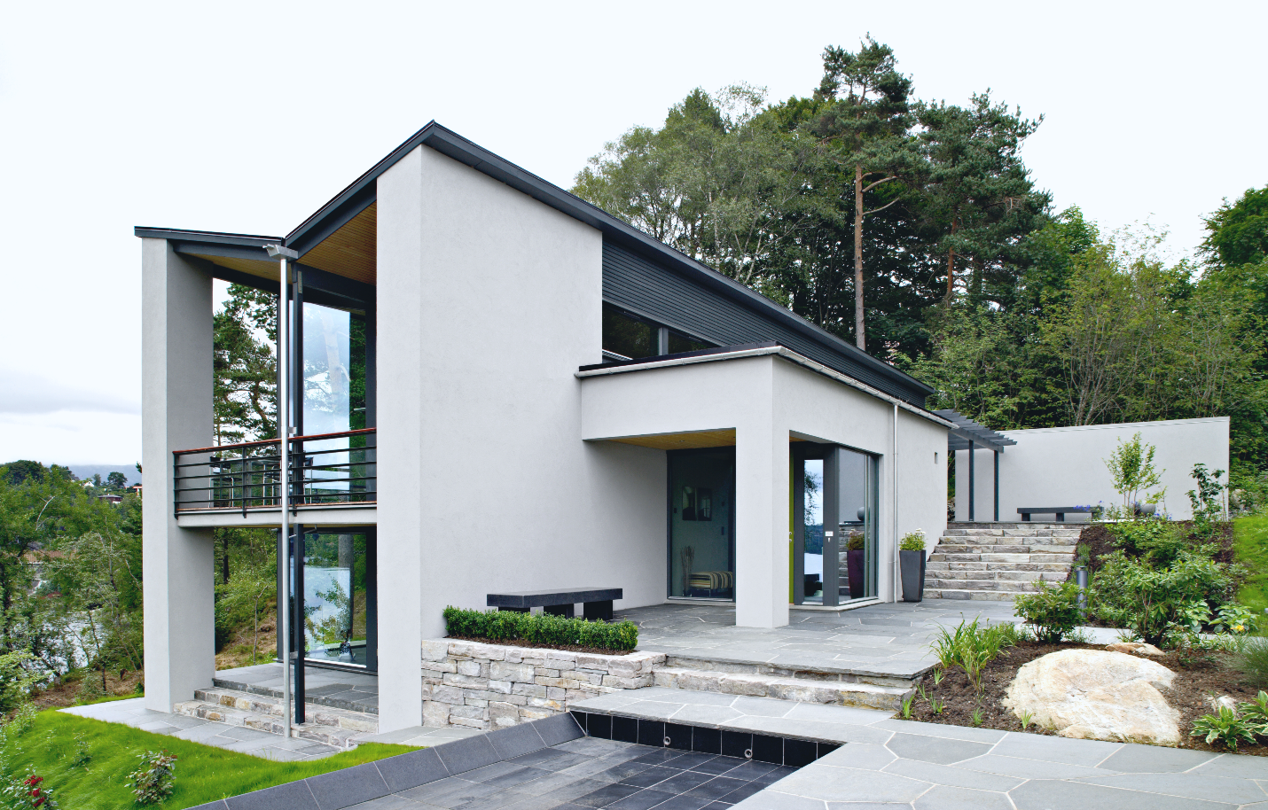 A concrete contemporary home with stark angles, an inverse roof, and a small pool.