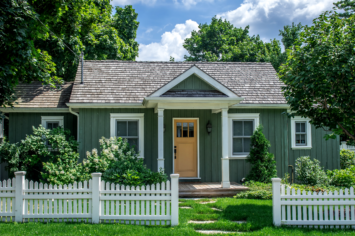 A one-floor cottage styled home with modest pillars holding the roof above the front door.