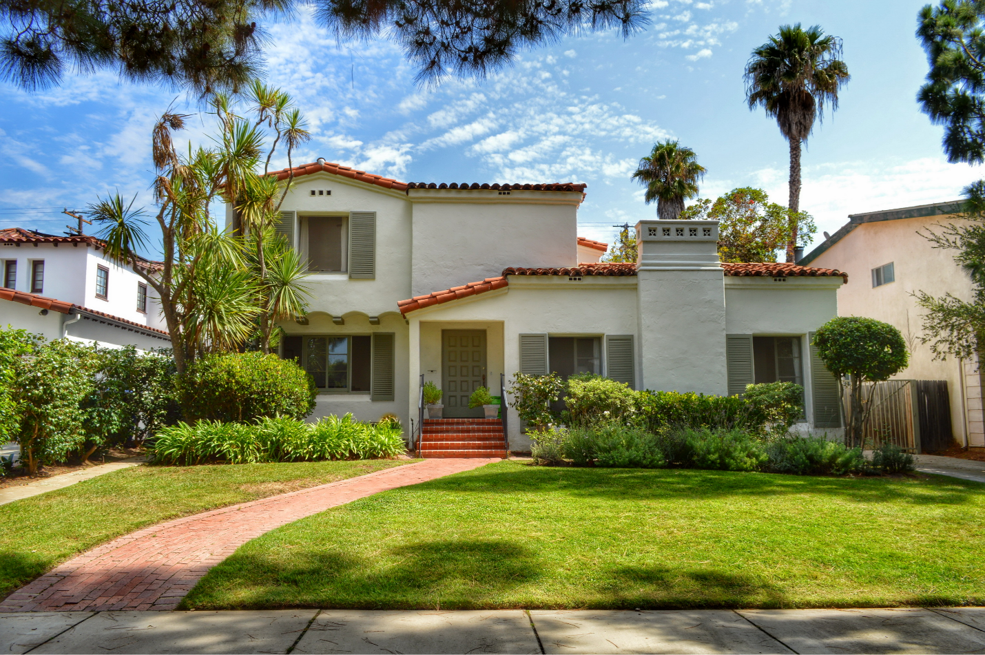 A stucco two-story mediterranean home with a red tiled roof and detailing.